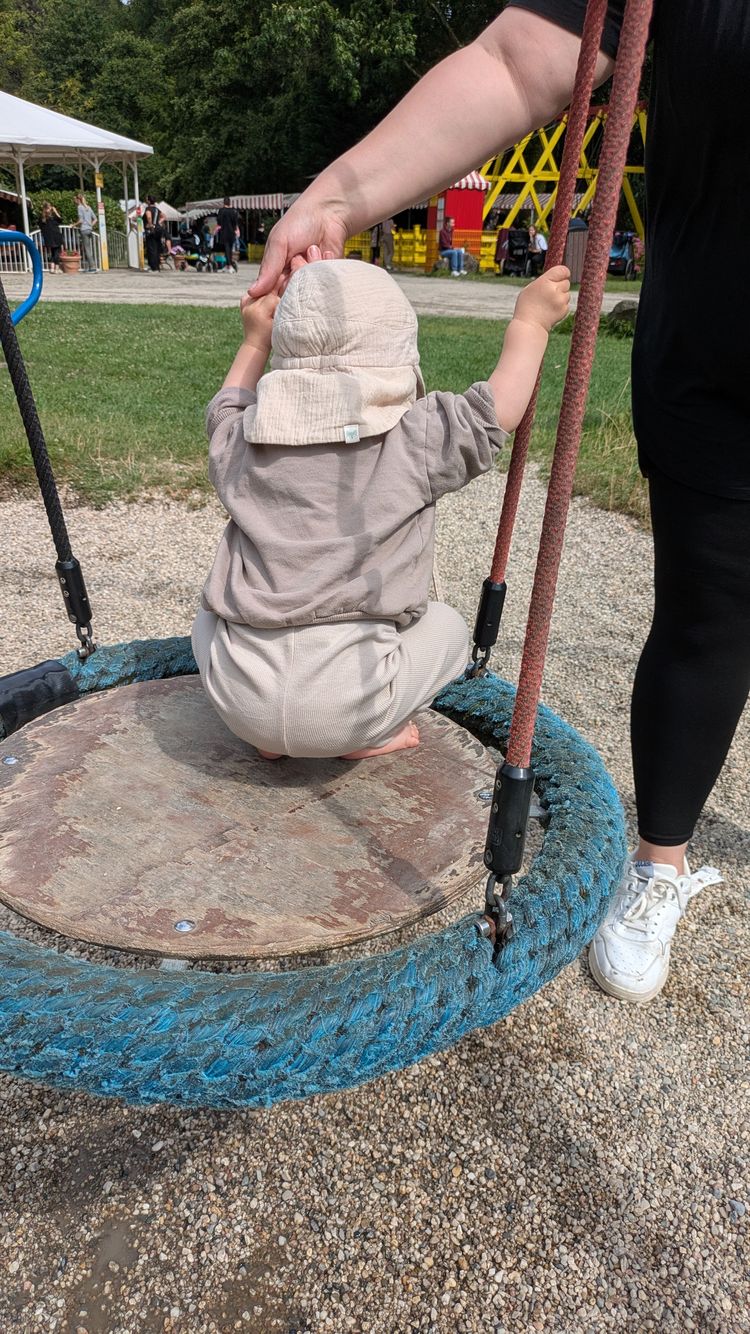 Ein kleines Baby sitzt auf einer Schaukel im Freizeitpark Schloss Beck.